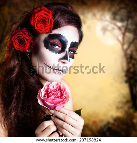 attractive young woman with sugar skull makeup and a rose in the hand