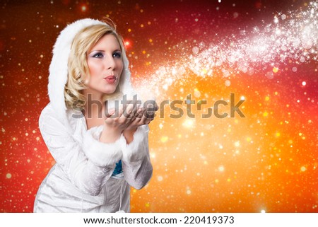 attractive girl in winter outfit blowing twinkling stardust