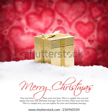 golden gift box in the snow in front of a heart background