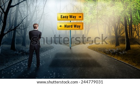 businessman standing on a crossroad having to decide to take the easy or the hard way