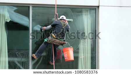 Window washer cleaning building facade. Person cleaning building window