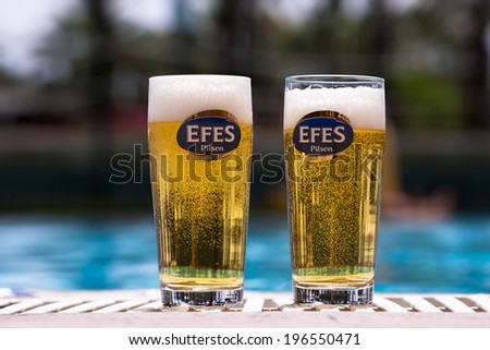 Belek, Turkey-June 2, 2014: A couple of Efes beer glasses on the pool edge. Efes Beverage Group, named after the ancient city of Ephesus, is market leader in Turkey, in Moldova and in Georgia