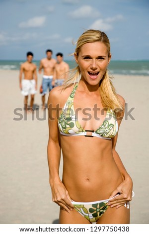 Young woman wearing bikini on summer beach vacation with friends smiling at camera