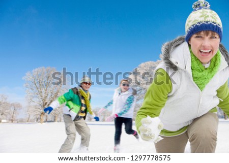 Mother and children having snowball fight in snowy landscape smiling at camera