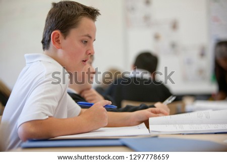 Male high school student working at desk in classroom