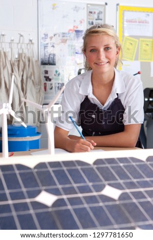 Female student studying wind solar power sources at school smiling at camera
