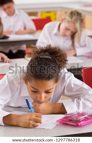 Female high school student taking test at desk in classroom