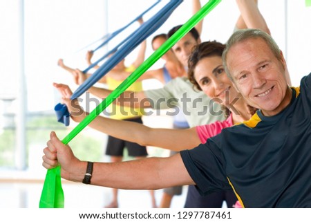 Men and women with resistance bands in exercise class smiling at camera