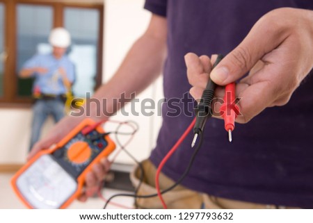 Detail of electrician working in house holding voltage meter