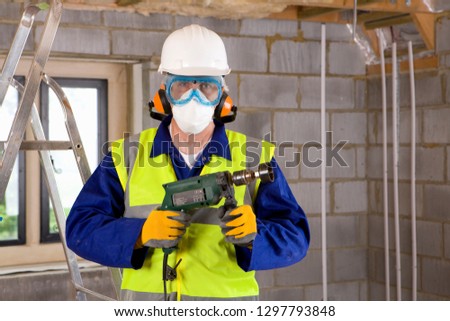 Construction worker wearing protective mask goggles and ear defenders