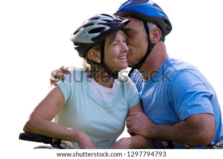 Cut out of active senior couple in cycle helmets on bike ride kissing