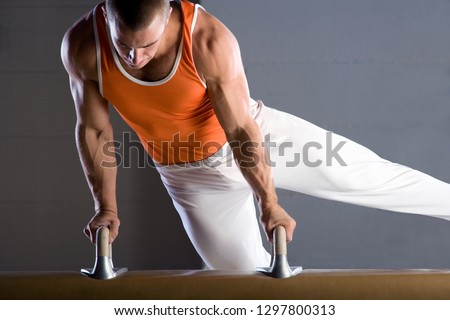Male gymnast performing on pommel horse in competition