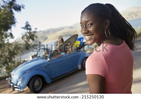 Teenage girl smiling, friends in car with surfboard, portrait, focus on foreground (tilt)