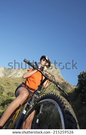 South Africa, female mountain biker adjusting cycling helmet strap, low angle view (tilt)
