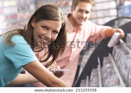 Young woman passing CD to man in record shop, bending down, smiling, side view, portrait, focus on foreground