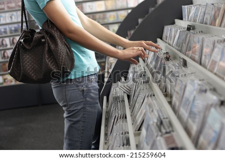 Young woman sifting through CDs in record shop, side view, mid-section