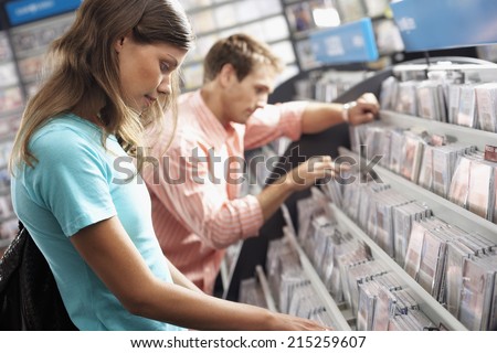 Young couple sifting through CDs in record shop, side view (tilt)