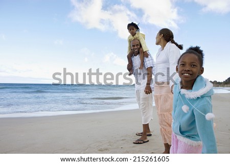 Two generation family walking on sandy beach, holding hands, smiling, side view, portrait (tilt)