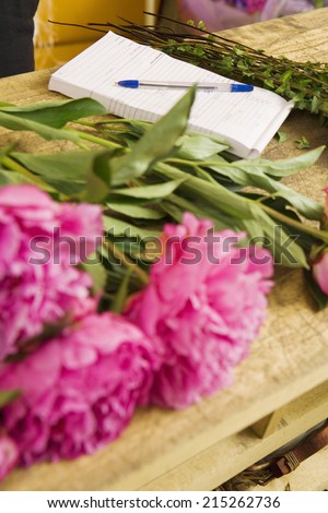 Pink flowers on table beside order pad in flower shop, close-up (still life)