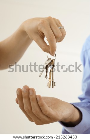 Woman handing man set of keys, close-up of hands, side view