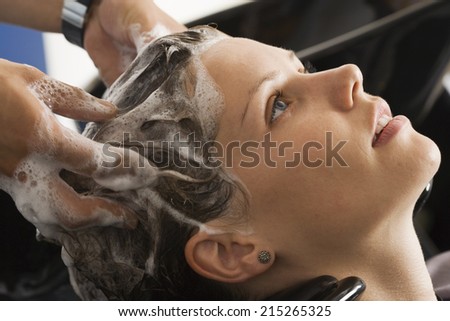 Hairdresser shampooing woman\'s hair in salon, close-up, profile
