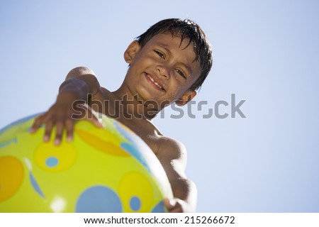 Boy holding green beach ball, smiling, portrait, upward view, unusual angle