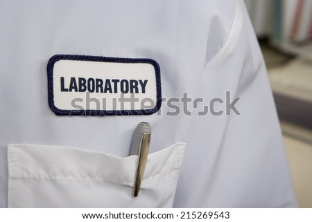 White laboratory coat, focus on label, pocket and pen, mid-section, close-up