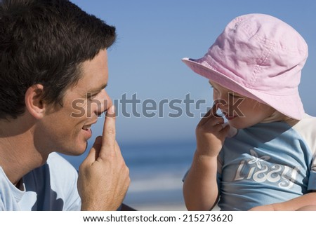 Father playing with daughter , touching noses with fingers, smiling, close-up, side view