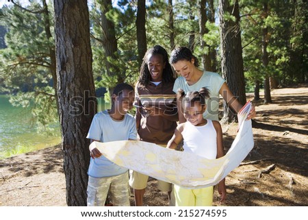 Family hiking on woodland trail, consulting map, smiling