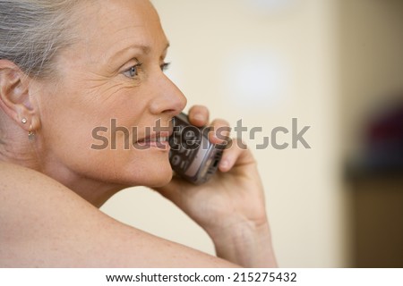 Senior woman using cordless phone, laughing, close-up, side view