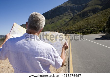 South Africa, Cape Town, mature man looking at map by road, rear view