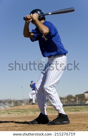 Baseball batter facing pitcher during competitive game, focus on foreground, rear view