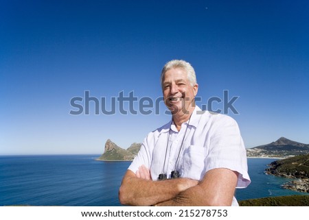 South Africa, Cape Town, senior man standing by sea, smiling, portrait