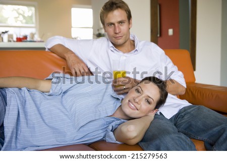 Woman lying on man\'s lap on sofa, smiling, portrait