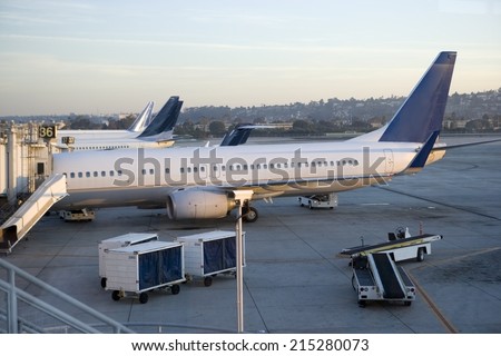 Stationary commercial aircraft at airport boarding gate, side view, elevated view