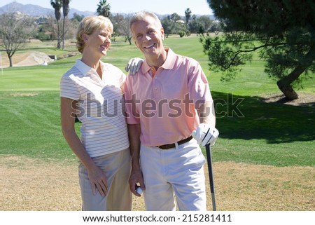 Mature couple standing on golf course, playing golf, woman leaning on manÃ?Â¢Ã¢Â?Â¬Ã¢Â?Â¢s shoulder, smiling, portrait