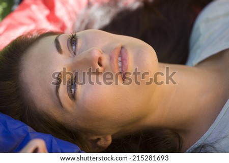 Woman lying on sleeping bag, daydreaming, side view, close-up