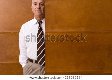 Mature businessman standing by wall, portrait