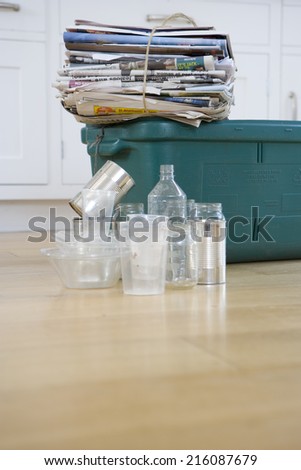 Newspaper bundle on recycling bin by empty glass jars and tin cans