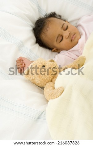 Baby girl (3-6 months) asleep in bed with soft toy