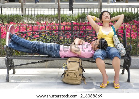 Couple on park bench, man resting head on woman\'s lap