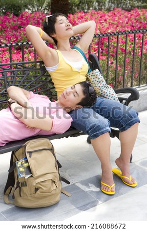 Man resting head on woman\'s lap on park bench, eyes closed, close-up