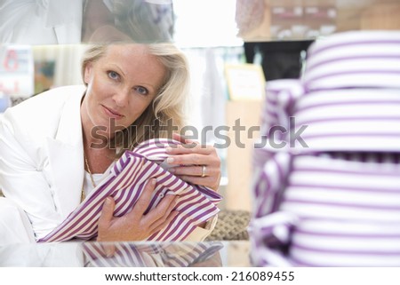 Mature female shop assistant adjusting shirt for display, portrait
