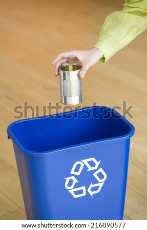 Man putting tin can into recycling bin, close-up of hand