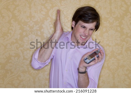 Businessman preparing to hit mobile phone, pulling face