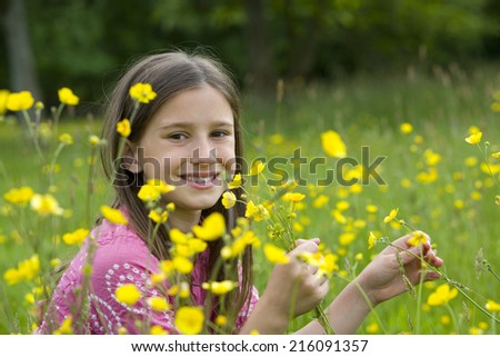 Girl (7-11) in field of wild flowers, smiling
