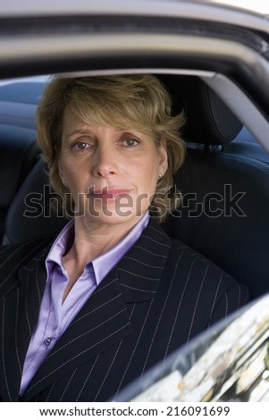 Mature businesswoman in back of car, smiling, portrait