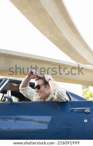 Young man in car combing hair in rear view mirror, side view