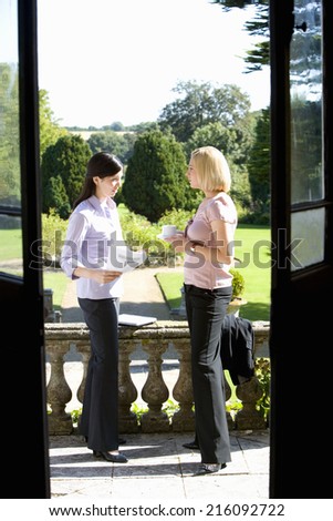 Businesswoman in conversation with colleague outdoors, view through open doors