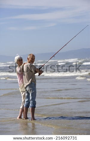 Senior couple fishing at beach, smiling, portrait
